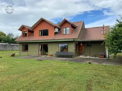 Gran casa de estilo sureño en venta en el sector Las Mulatas de Valdivia, con un amplio terreno de césped, una propiedad familiar de Gestión inversión.