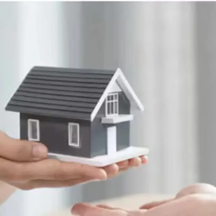 Una persona entrega un modelo de casa a otra, simbolizando el traspaso de una propiedad gestionado de forma segura y profesional por el equipo de Gestión inversión.