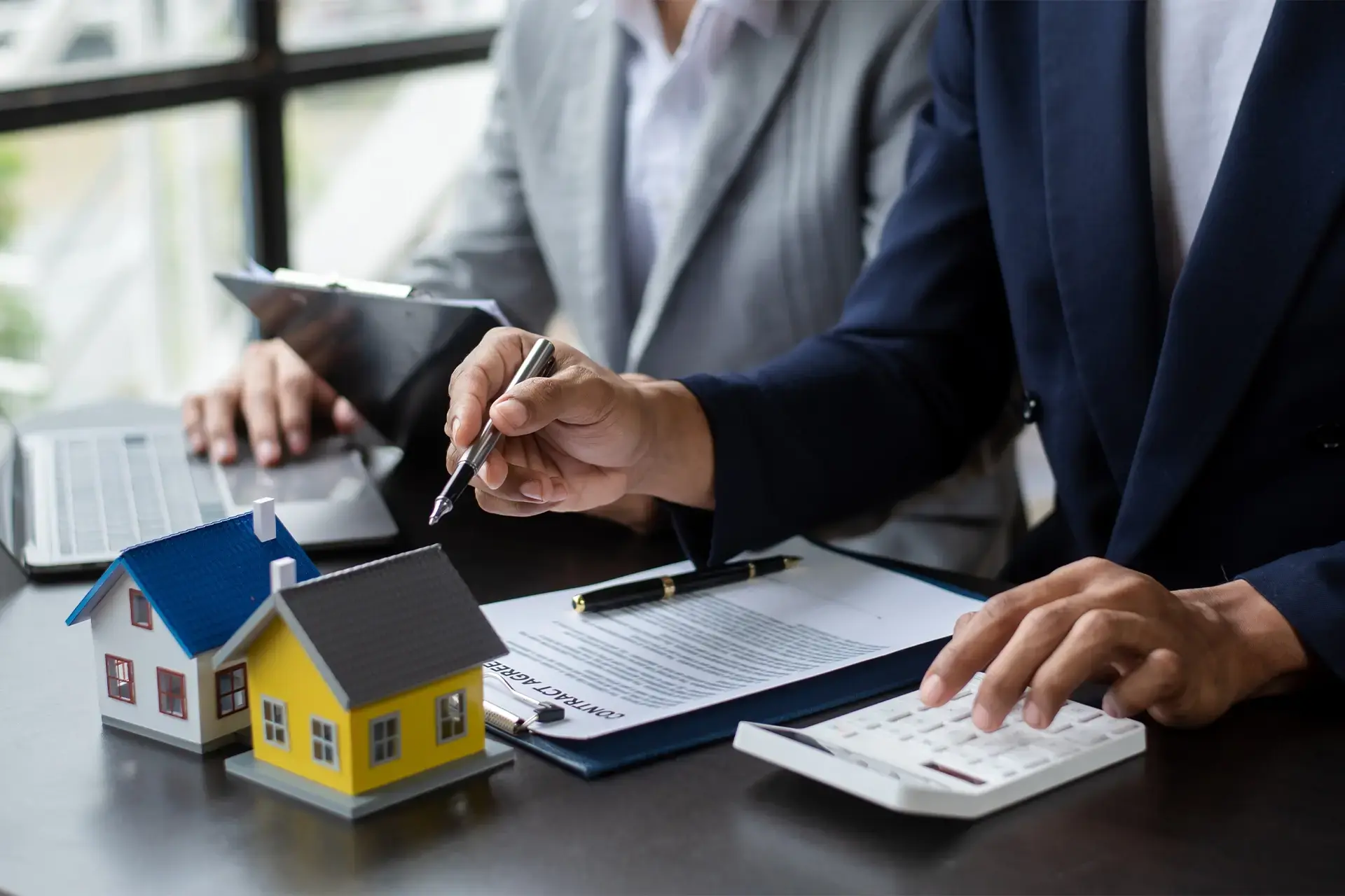 Profesionales revisando documentos y calculando costos relacionados con la compra o regularización de propiedades inmobiliarias