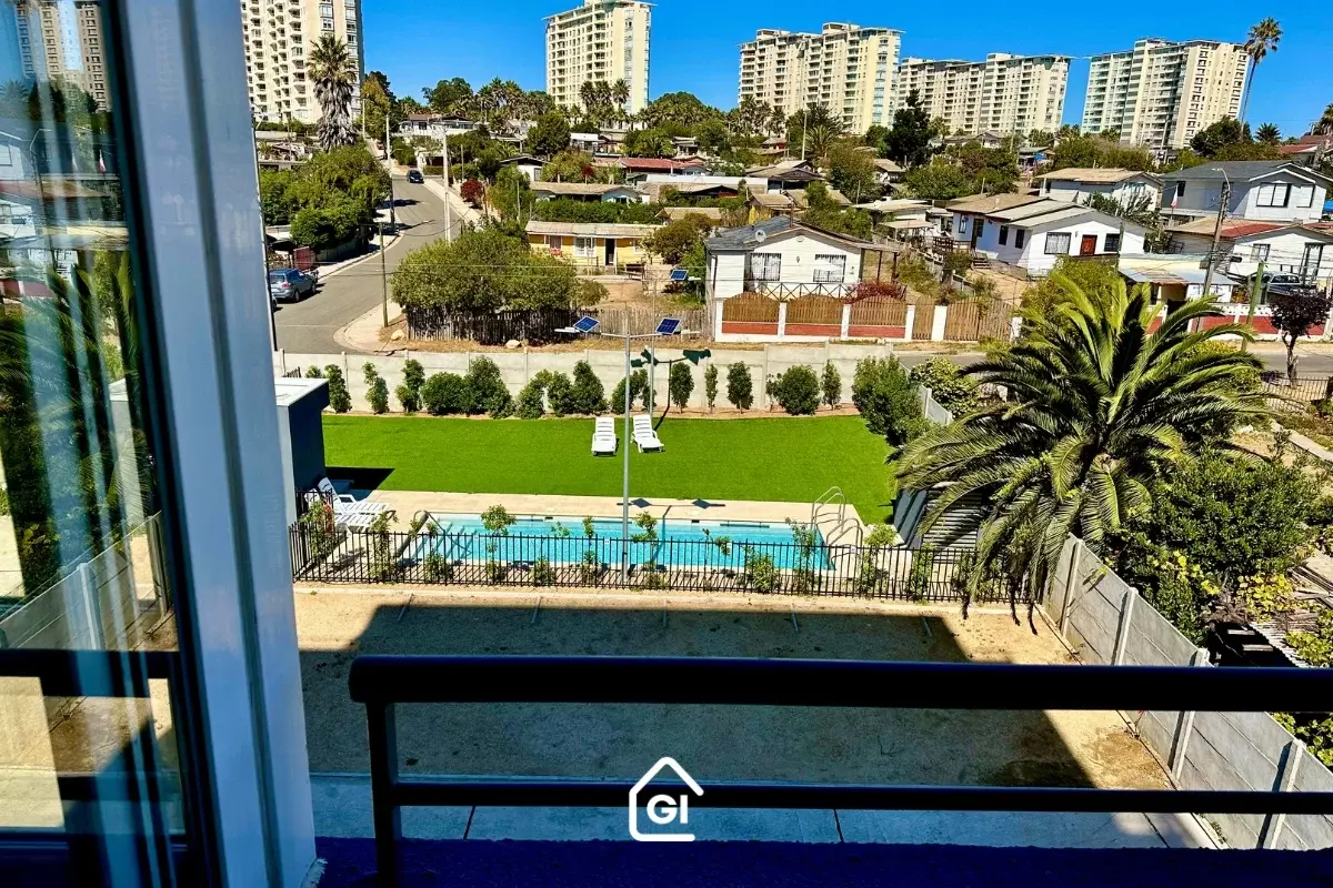 Vista desde la terraza de un departamento en Algarrobo, que incluye la piscina y áreas verdes del edificio, una propiedad ideal para inversión y arriendo vacacional con Gestión inversión.